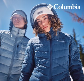 Zwei Personen tragen Columbia-Pufferjacken und Beanies im Freien unter einem klaren blauen Himmel, mit dem Columbia-Logo.