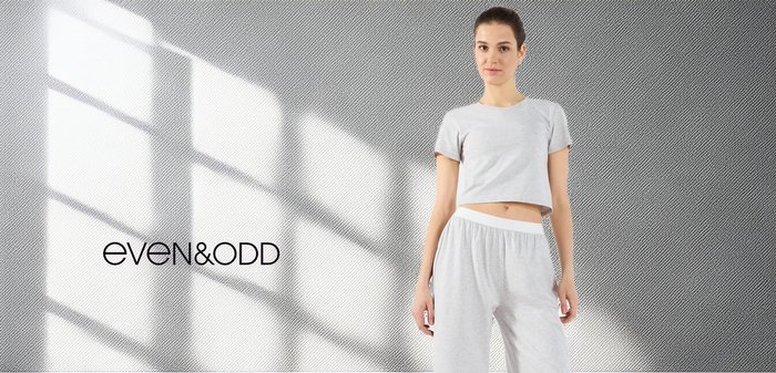 Grijze cropped t-shirt met korte mouwen en bijpassende lichte broek met een elastische tailleband; gladde textuur met subtiele ontwerpelementen.