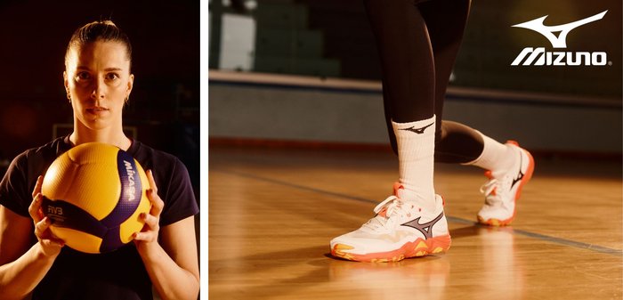 Balón de voleibol Mizuno, amarillo con acentos azules, sostenido por una persona. A la derecha, un pie con una zapatilla blanca y naranja, extendiéndose sobre una cancha de madera.
