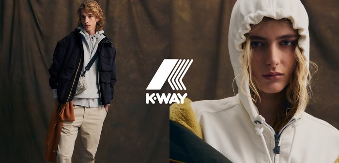 Giacca nera con zip, felpa leggera grigia con cappuccio, felpa color crema con cappuccio e cordino, pantaloni beige, modello in posa con una borsa a tracolla.