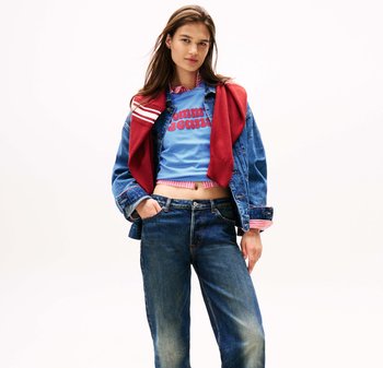 Denim jacket over blue cropped t-shirt with red "Tommy Jeans" lettering, paired with loose blue jeans. Red sweater draped around the shoulders.