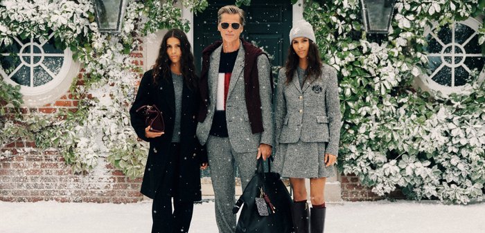 Drei Personen stehen in einer verschneiten Umgebung. Sie tragen Kleidung aus unterschiedlichen Texturen in neutralen Tönen, ergänzt durch Accessoires wie Hüte und Taschen.