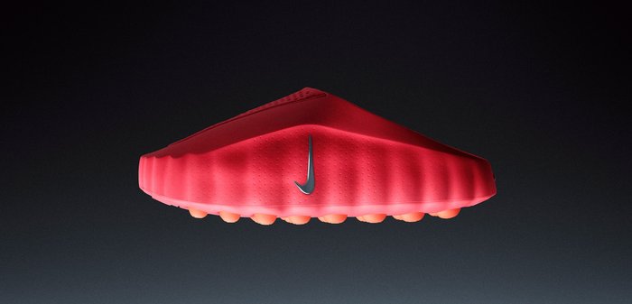 Red Nike shoe with a smooth, aerodynamic design. Features a textured upper and a round sole with multiple rubber studs for traction.