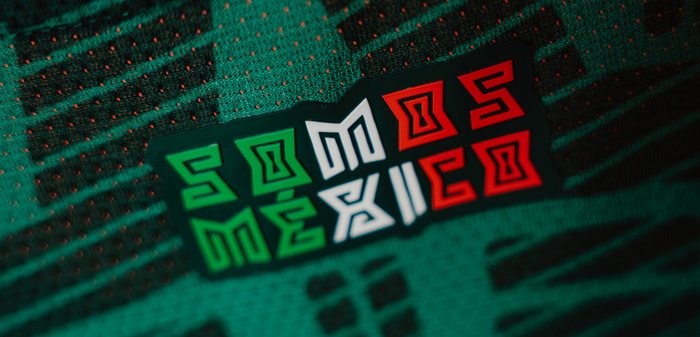 Zielona tkanina z teksturowanym wzorem, z odznaką z napisem "SOMOS MÉXICO" w stylizowanym zielonym, białym i czerwonym. 