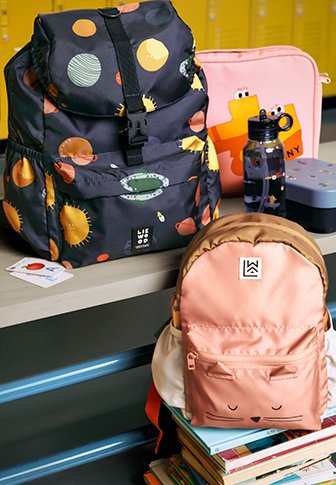 Mochila preta com design de planetas coloridos, aba arredondada e logotipo. Mochila menor em pêssego com detalhes faciais, textura suave e bolso com fecho na frente.