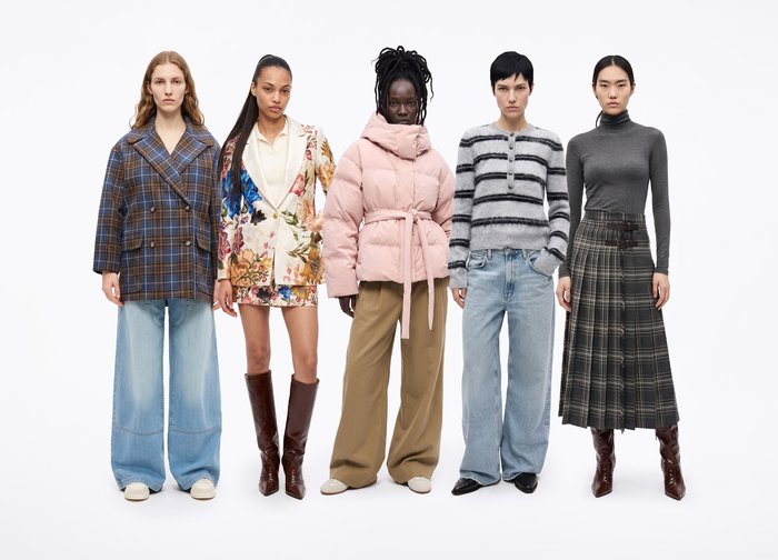 Cinq mannequins posent en rang, vêtus de tenues variées, notamment des manteaux à carreaux, une robe à fleurs, une doudoune rose, des mailles rayées et une jupe à carreaux.