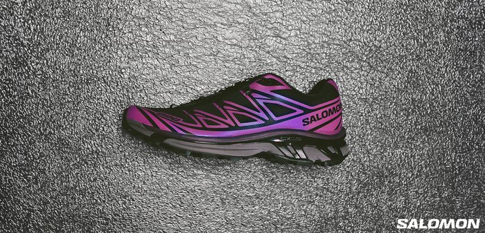 Black and purple running shoe featuring a sleek design, engineered mesh upper, striking patterns, and a prominent "SALOMON" logo on the side.