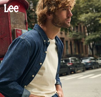 Chemise en denim à boutons de couleur bleu foncé sur un t-shirt blanc, avec une coupe décontractée. L'arrière-plan présente une cabine téléphonique vintage rouge et une scène de rue urbaine.