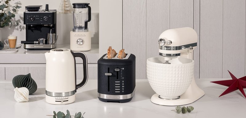 Bouilloire blanche, grille-pain noir à deux fentes avec minuterie, robot mixeur argenté avec un bol texturé, et un blender. Le tout dans une cuisine moderne.
