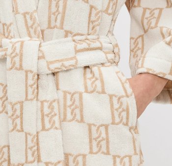 Mjuka, strukturerade badrock i krämfärg med ett återkommande geometriskt mönster i beige. Har ett knytbart midjebälte och sidofickor.