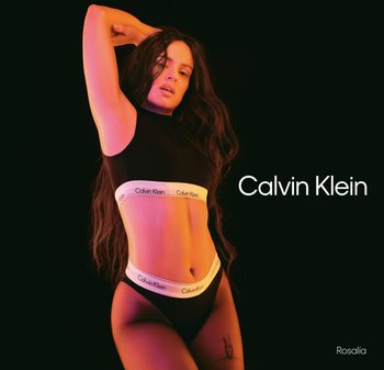 Svart bomullscrop top och hög midja underkläder med en vit Calvin Klein logoband. Modellen poserar mot en mörk bakgrund med färgad belysning.