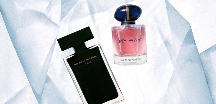 Deux flacons de parfum sur un tissu blanc froissé : Narciso Rodriguez "for her" en noir, et Giorgio Armani "My Way" en rose avec un bouchon bleu.