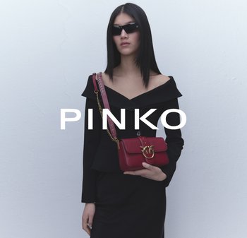 Red leather handbag with a gold hardware clasp, featuring a chain strap and a smooth texture, held by a person in a black off-shoulder top.