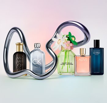 Fem parfymflaskor ordnade med en metallisk, skulptural ställning. Flaskorna varierar i form och färg: svart, genomskinlig, grön, rosa och blå.