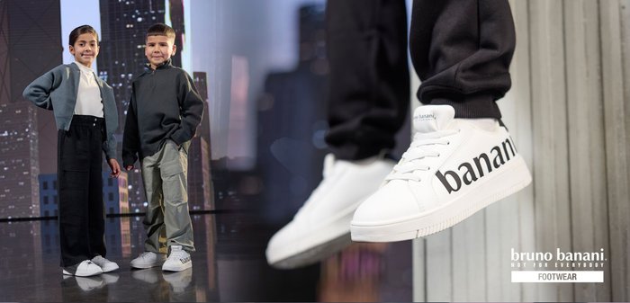 Hvide sneakers med et sort "banani" logo, glat materiale, rundt tå og struktureret gummisål, parret med afslappet tøj.