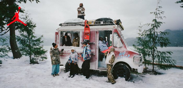 Sept personnes en vêtements d'hiver se rassemblent autour d'un camion de crème glacée couvert de neige, avec des skis sur le toit, près d'un lac enneigé et d'arbres.