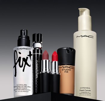 Sex MAC-kosmetikprodukter: en genomskinlig sprayflaska, ett svart rör, två röda läppstiftskulor, en foundationflaska och en rengöringsolja, arrangerade på en mörk bakgrund.