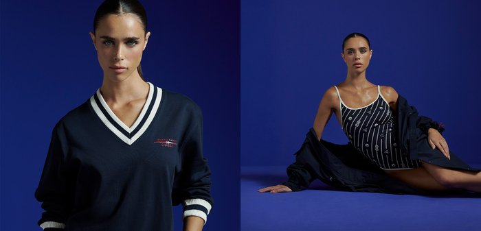 Młoda kobieta z zaczesanymi do tyłu włosami, ubrana w granatowy sweter z dekoltem w serek, białymi paskami i czerwonym logo "North Sails Guess" na piersi, na ciemnoniebieskim tle.