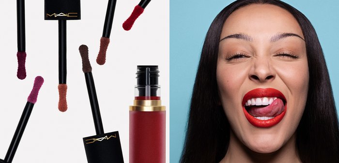 Femme aux longs cheveux bruns et lèvres rouges vives se léchant les lèvres sur un fond bleu clair, portant un haut à bretelles noir.