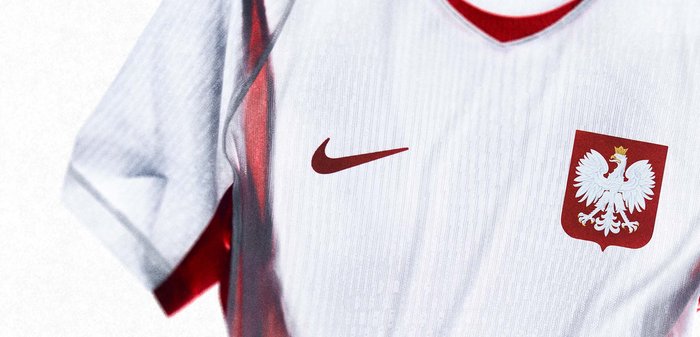 Λευκό αθλητικό φανέλα με κόκκινες λεπτομέρειες, λογότυπο Nike και εθνικό έμβλημα της Πολωνίας με έναν στεφανωμένο λευκό αετό στο στήθος.