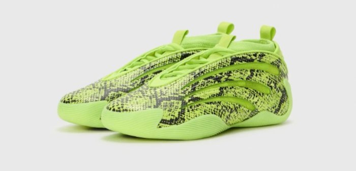 Paire de chaussures de sport vert néon avec motif tacheté noir et semelles nervurées, vue latérale inclinée sur fond blanc.