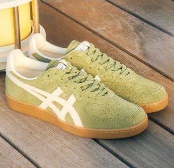 Baskets en suede vert avec des accents blancs, présentant un bout perforé, des lacets texturés et une semelle en caoutchouc naturel. Design classique de type basse.