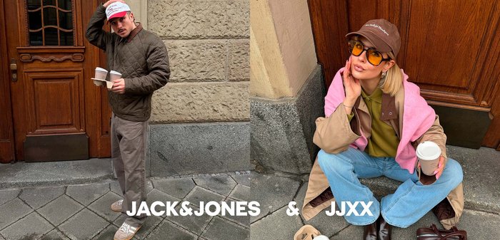 Man in white and red cap drinking coffee beside smiling woman with pink scarf, yellow sunglasses, and brown handbag in café setting.