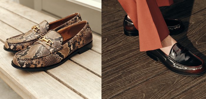 Glanzende zwarte lederen loafers gedragen met roestkleurige broeken op een donkere houten vloer, waarbij de schoen details en stoftextuur worden benadrukt.