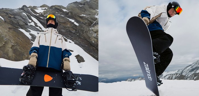 Snowboard avec une surface supérieure noire arborant un logo blanc "Zalando", tenu par une personne portant une veste bleue et blanche avec des gants, sur la neige.