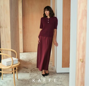 Bordeaux gebreide polo sweater met korte mouwen, gecombineerd met een lange, vloeiende bordeaux satijnen rok. Zwarte puntige hakken maken de outfit compleet.
