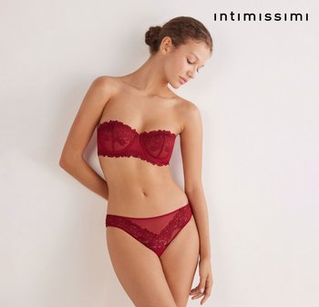 Reggiseno senza spalline in pizzo rosso e slip in pizzo trasparente abbinato, con motivi floreali intricati e bordi ondulati. Texture liscia, design aderente.