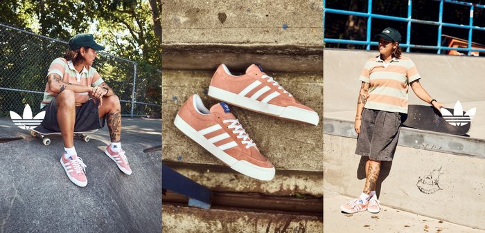 Persona con tatuajes lleva una camisa de rayas y zapatillas Adidas rosas, sentada en una tabla de skate sobre una rampa de concreto en un parque de patinaje.