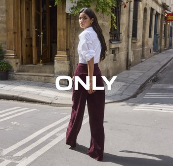 Witte blouse, diep bordeaux brede pijpen met een gestructureerde stof, staande op een straat met kasseien en zonlicht. Tekstoverlay: "ENKEL."
