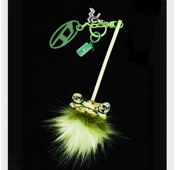 Portachiavi con cinturino in pelle verde, pompon peloso giallo-verde, ciondolo a forma di rana metallico e targhetta con logo Diesel verde su sfondo nero.