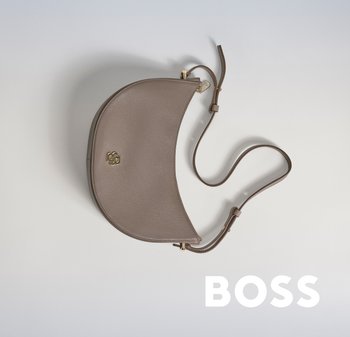 Sac à épaule en cuir brun avec une silhouette incurvée, quincaillerie dorée et bandoulière amovible. Il présente une surface texturée et un détail de logo.
