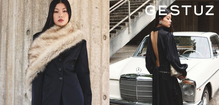 Crna krojena haljina s dubokim otvorom na leđima, naglašena bež umjetnim krznenim šalom. Srebrni remen od lanca, model kraj vintage bijelog Mercedesa.