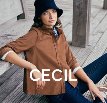 Bruine button-up overhemd met kraag, opgerolde mouwen, gecombineerd met donkere jeans. Een marineblauwe bucket hat en een blauwe sjaalaccentueren de look.