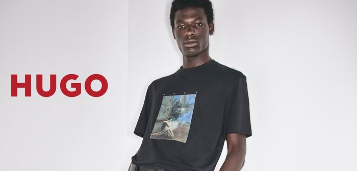 Black short-sleeve t-shirt featuring a graphic print on the front, paired with loose-fitting black trousers and a belt with a rectangular buckle.