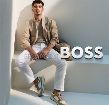 Jonge man in een beige jas, witte broek en sneakers zit zelfverzekerd op witte trappen naast de tekst "Word de volgende BAZEN."