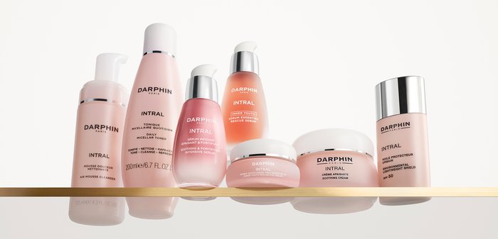 Sept produits de soin Darphin Intral dans des nuances de rose variées. Les flacons affichent des designs élégants, avec des accents argentés et des étiquettes claires.