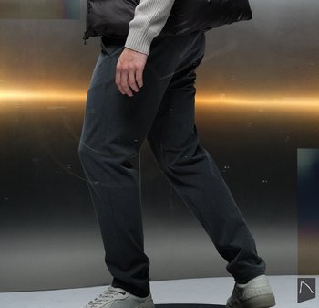 Donkergrijze, op maat gemaakte broek van soepele stof, met een rechte pijp. Gecombineerd met lichtgekleurde sneakers.