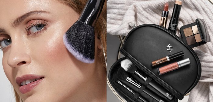 Trousse de maquillage noire avec fermeture éclair et logo KIKO, contenant divers cosmétiques : rouges à lèvres, enlumineur, palette d'ombres à paupières et pinceaux de maquillage avec des accents argentés.