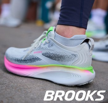 Lichtgrijze hardloopschoen met bovenwerk van mesh, neon groene accenten en een roze naar gele verloopzool. Voorzien van grijze veters en een gevoerde kraag.