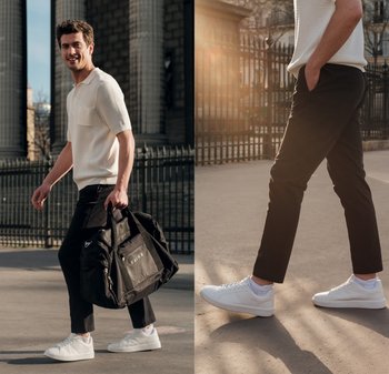 Weißer gestrickter Kurzarm-Pullover, schwarze taperte Hose, weiße Sneakers und eine schwarze Duffel-Tasche mit Reißverschluss und Logo an der Seite.