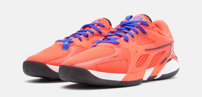 Chaussures de sport orange vif avec un design en mesh, des lacets bleus, des accents texturés, et une semelle noire et blanche avec un motif de crampons.