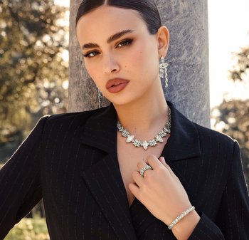 Set di gioielli in argento con una collana importante, orecchini coordinati e un braccialetto con un design floreale e accenti scintillanti.
