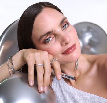 Silver jewelry includes a bracelet with links, two rings with stone accents, and earrings with dangling strands, set against a neutral background.