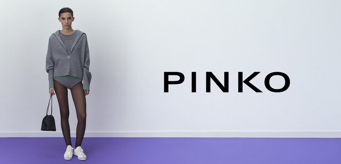 Gray knitted hoodie with green accents, paired with a gray bodysuit, sheer black tights, and white sneakers. Black drawstring bag.