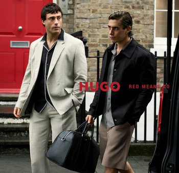 Dos hombres con atuendos elegantes están junto a un vehículo negro; uno sostiene una bolsa negra grande, con el texto "HUGO RED MEANS GO" superpuesto.