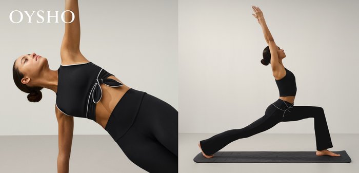 Frau in schwarzer Sportbekleidung, die eine seitliche Plank-Übung mit einem erhobenen Arm vor einfachem hellem Hintergrund ausführt.